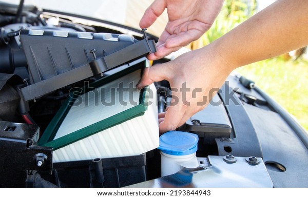 Replacing a new air filter in a passenger car,\
engine compartment. Car maintenance. Automotive mechanic installs a\
new engine air\
filter.