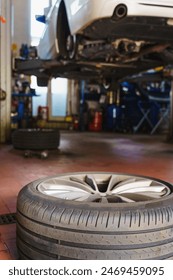 Replacing summer tires for winter using pneumatic wrench tool by mechanic worker after balancing wheels in car service garage shop