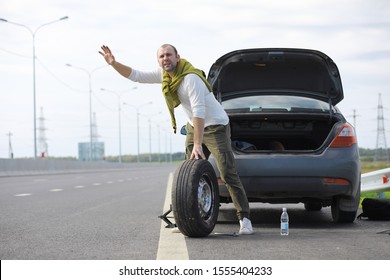 Replacing The Wheel Of A Car On The Road. A Man Doing Tire Work On Sidelines.