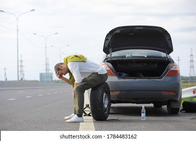 Replacing The Wheel Of A Car On The Road. A Man Doing Tire Work On Sidelines.