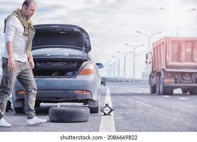 Replacing The Wheel Of A Car On The Road. A Man Doing Tire Work On Sidelines.