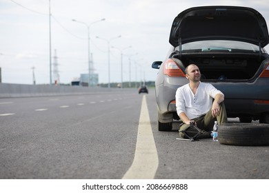 Replacing The Wheel Of A Car On The Road. A Man Doing Tire Work On Sidelines.