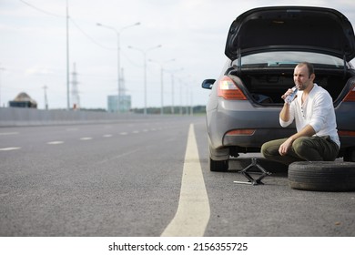 Replacing The Wheel Of A Car On The Road. A Man Doing Tire Work On Sidelines.