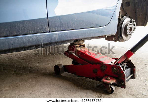 Replacing wheels on a car, jack holds the\
body in raised position. Car without wheel and lift up by\
hydraulic, waiting for tire\
replacement.