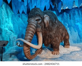 a replica of a mammoth with long tusks is in a museum