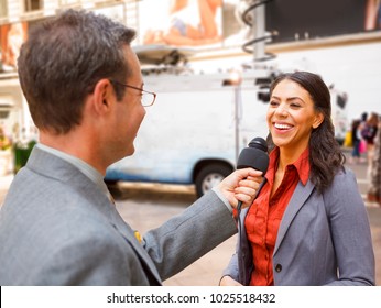 Reporter with mic interviews woman on the street.