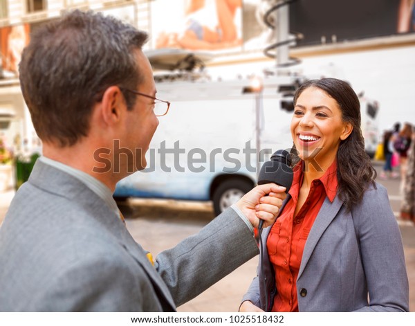 Reporter with\
mic interviews woman on the\
street.