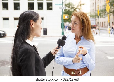 A Reporter With A Microphone Interviews A Woman.