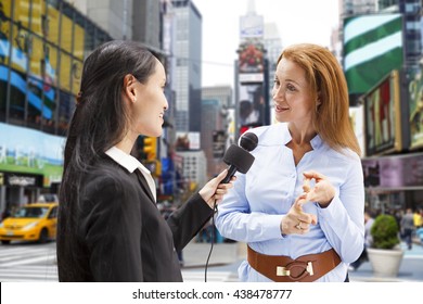 A Reporter With A Microphone Interviews A Woman In Times Square New York City.