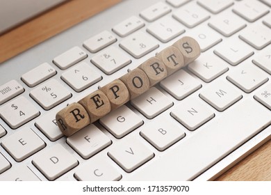 Reports word on cube wood with keyboard background - Powered by Shutterstock