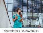 Representation of the daily life of a nurse going to work. Young, confident nurse outside looking away with smile on her face. Nursing or medical student walking to class on hospital campus