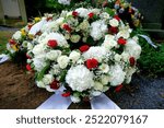 Representative white funeral wreath of hydrangeas, roses, daisies, gypsophila and some red roses on a grave after a funeral