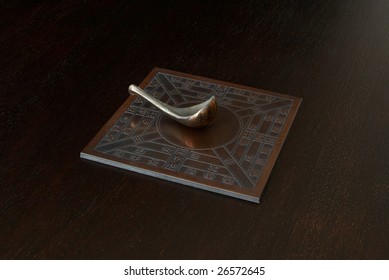 Reproduction of an ancient Chinese compass (which points south) on a dark wooden bench