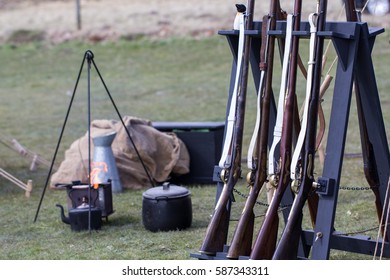 Reproduction Vintage Muskets At A Military Camp Fire. Napoleonic War Reenactment Musket Rifles. Selective Focus On Foreground.