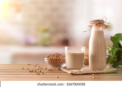 Reptientes with soy milk and grains on a wooden table and rustic kitchen background. Alternative milk concept. Front view. Horizontal composition
