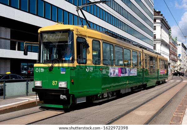 Republic of Finland, Helsinki, South Harbor: Street\
scene with yellow green public transport streetcar in the city\
center of the Finnish capital - concept transportation traffic\
travel. Jul 29, 2019