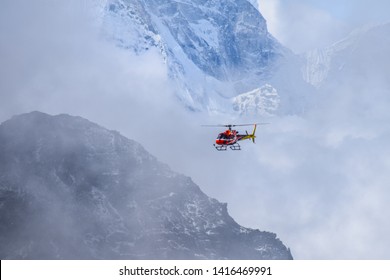 Rescue Helicopter In Clouds Flying Between Snow Mountains