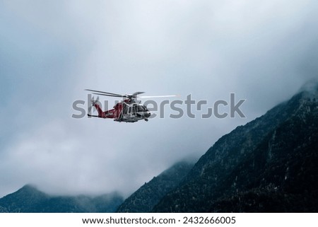 rescue helicopter in flight between clouds and mountains