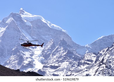 Rescue Helicopter In Flight Over Snow Capped Mountains