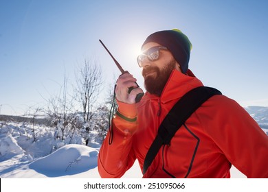 Rescue man talking with portable radio on mountain snow landscape. Back light image.