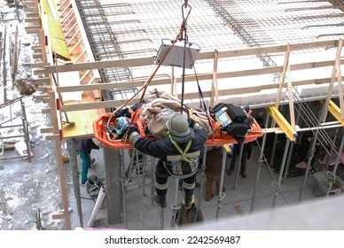Rescue operations of a worker inside a construction site. A firefighter recovers an injured person with the ladder and stretcher - Shutterstock ID 2242569487