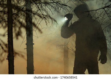 Rescue Search. Men Wearing Camouflage Clothing With Powerful Flashlight Between Trees And Fire Smoke. Forest Wildfire Rescue Mission. 