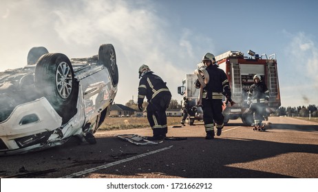 Rescue Team of Firefighters Arrive on the Car Crash Traffic Accident Scene on their Fire Engine. Firemen Grab their Tools, Equipment and Gear from Fire Truck, Rush to Help Injured, Trapped People
