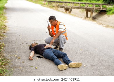 A rescue workers using radio communication calling for help team ะo help a man lying unconscious on the road from an accident. - Powered by Shutterstock