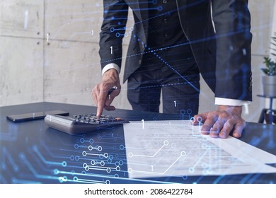 A research and development specialist computing the data to create a new approach to develop high tech business. Technological icons over the desk with calculator. - Shutterstock ID 2086422784