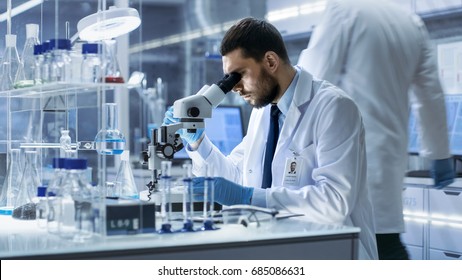 Research Scientist Looks into Microscope in Research Centre. He's Conducts Experiments in Modern Laboratory.