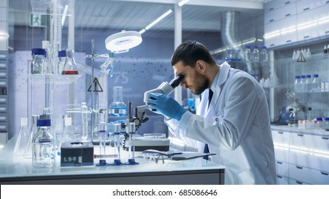 Research Scientist Looks Into Microscope. He's Conducts Experiments In Modern Laboratory.