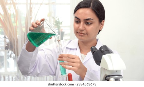 Researcher asian woman wear lab cost work mixing test tube specialist sample chemist equipment with microscope at laboratory. Student young girl examining biotechnology health medical. Health science. - Powered by Shutterstock