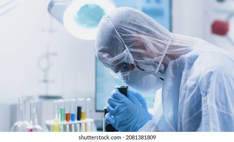 Researcher doctor with ppe equipment looking into medical microscope analyzing virus sample during vaccine development experiment in biochemistry hospital laboratory. Medicine concept - Shutterstock ID 2081381809