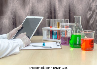 researcher doing experiment in the lab with a test tube, chemical fluid, and computer on the table