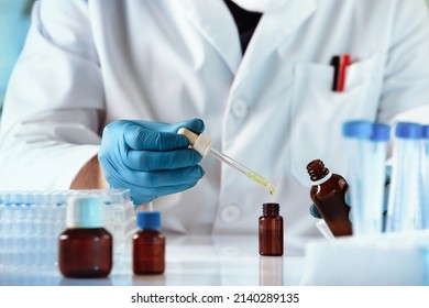 researcher dosing and mixing fluid liquids in the chemistry lab. hands of chemist pipetting in a bottle drop of yellow fluid perfume in the product research laboratory