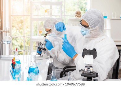 Researcher In Laboratory Personal Protective Equipment Suit Or PPE Conduct Experiment With Biohazard Virus Using Microscope To Discover Vaccine, Science And Medical Concept.