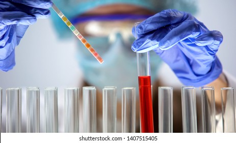 Researcher Measuring PH Level In Red Liquid Substance With Litmus Paper, Test