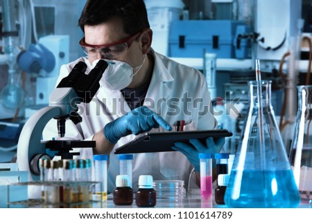 researcher using digital tablet and micro and working with samples in the lab / biochemical engineer working with microscope and tablet in the laboratory