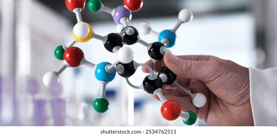 Researcher using a molecular model to understand a chemical formula in a laboratory. Chemistry research  - Powered by Shutterstock