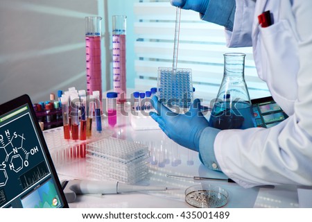 researcher working in a biotechnology lab / biochemical engineer working with microplate in a laboratory experiment