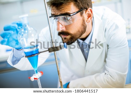 Researcher working with blue liquid at separatory funnel in the laboratory