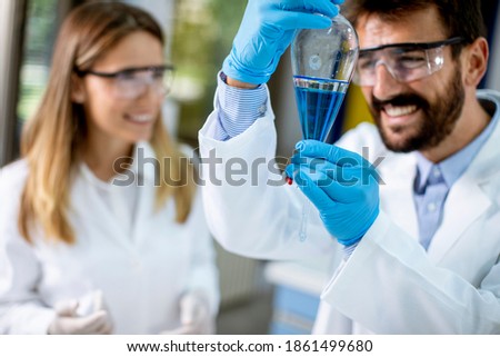 Researcher working with blue liquid at separatory funnel in the laboratory