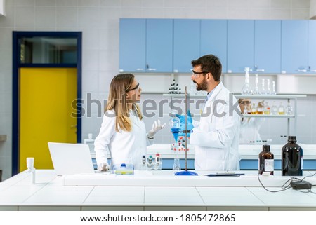 Researchers working with blue liquid at separatory funnel in the laboratory