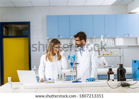 Researchers working with blue liquid at separatory funnel in the laboratory