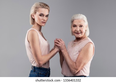 Resemble Daughter. Same Short-haired Woman With Grey Eyes But Different Ages Connecting Their Hands