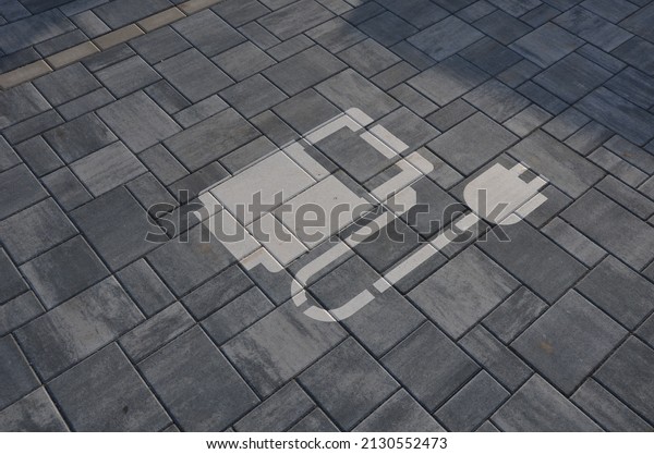 reservation of road\
signs for electric cars. Charging station with gas station symbol\
with cable and plug for charging the electric battery, sprayed on\
the parking lot\
tiles