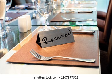 Reserved Metal Plate On The Table With Blurry Background. Reservation Seat At Restaurant.