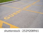 Reserved parking sign for Guest. Parking space with yellow painted sign of guests parking spot. Parking spot infront of corporation building or hotel.