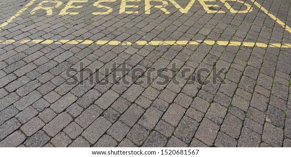 Reserved\
parking sign painted in yellow on stone\
pavement