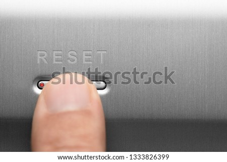 The reset button on the aluminum panel. Male finger